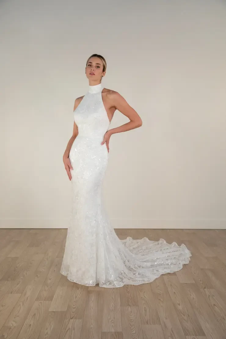 model is wearing a high neckline sleeveless sheath bridal gown with a train and open back