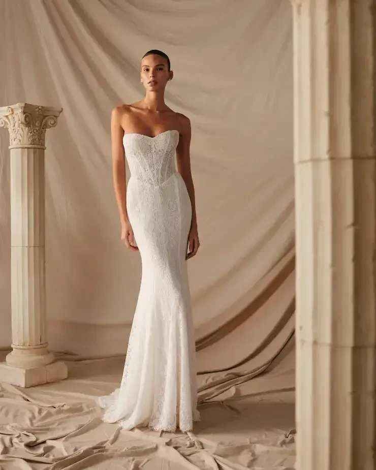 model is wearing a strapless fitted wedding dress with a corset bodice