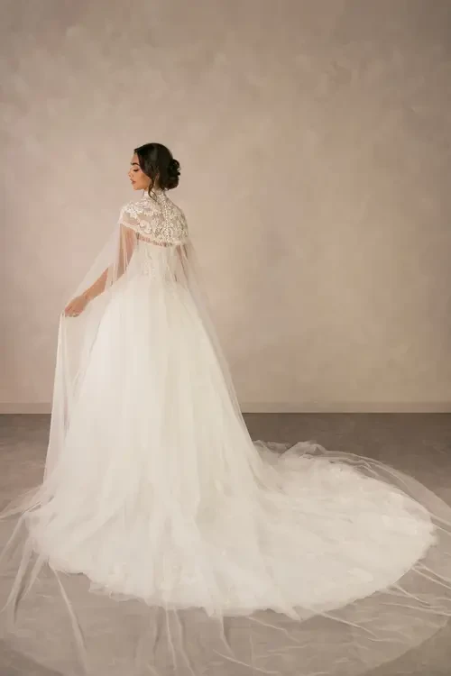model is wearing a strapless ball gown with a high neck lace capelet