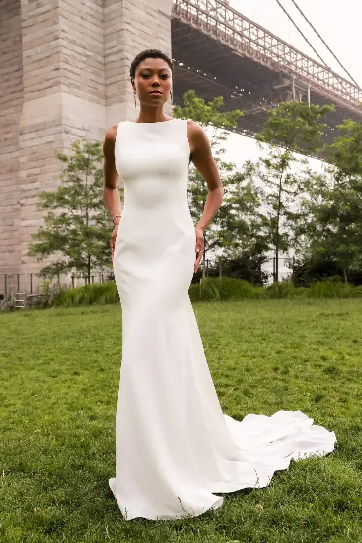 model is wearing a sleeveless sheath minimalist wedding gown