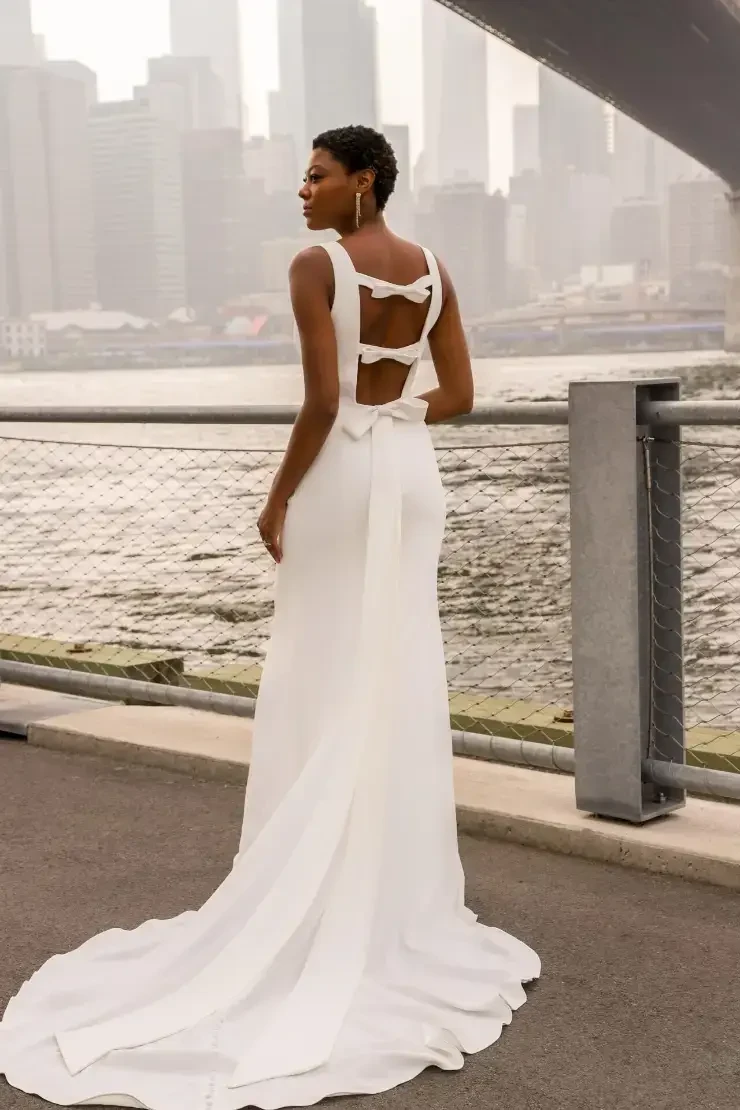 model is wearing a sleeveless sheath minimalist wedding gown
