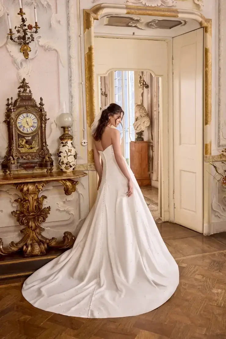 model is wearing a sleeveles bridal gown with pearl accents