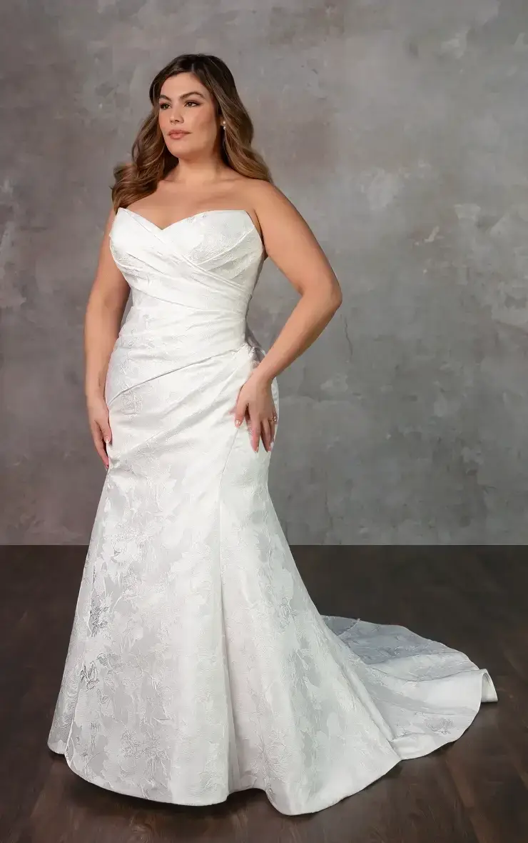 A woman wearing an elegant white wedding dress with a fitted bodice and a flowing train, posed against a neutral background.
